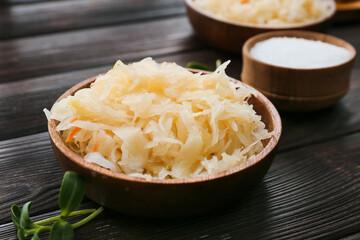 Bowl with tasty sauerkraut on dark wooden background