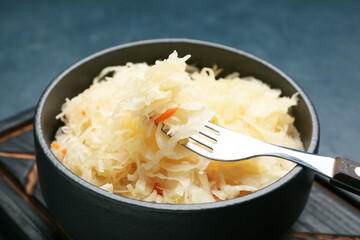 Bowl with tasty sauerkraut on dark background