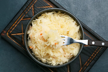 Bowl with tasty sauerkraut on dark background