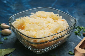 Bowl with tasty sauerkraut on color background