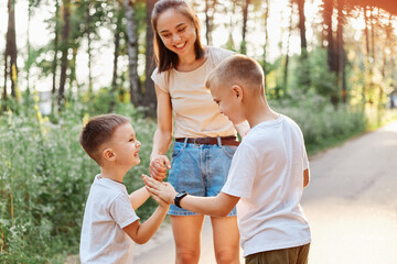 Family having fun while walking in summer park and laughing, little boy gives a high five to his...