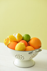 Colander with healthy citrus fruits on wooden table