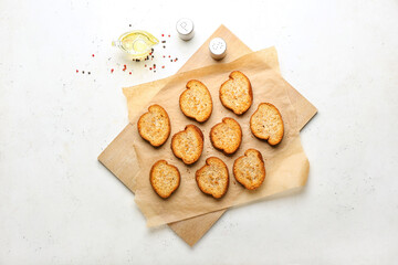 Wooden board with tasty toasted bread on light background