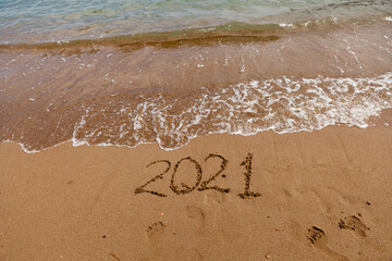 inscription on the sand 2021. symbol 2021 on the coast, overlooking the sea. Summer holidays in the new season.