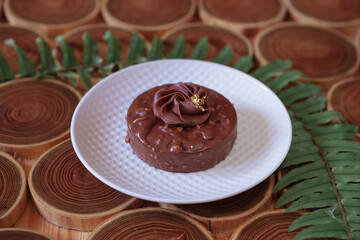 chocolate dessert with filling of caramel, nuts and nougats. The cake is covered with chocolate on a wooded background with a morning natural light