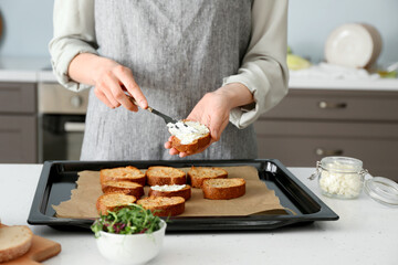 Female chef preparing toasts with cheese on kitchen table, closeup