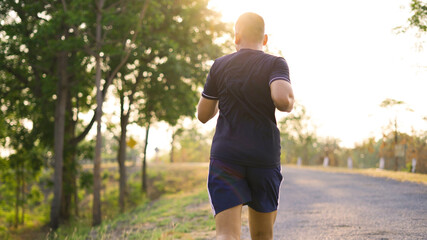 Sporty teenage boy running on natural park road with sunset time.