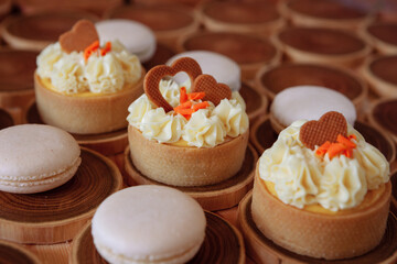 white delicate lowly macaroons on a wooden background. The pastel tone of the cream inside the French cookies
