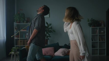 Aggressive wife screaming at husband, fighting, couple quarreling in the evening at home man and woman shouting at each other, gesturing. Scandal and crisis in family. Domestic violence, abuse.