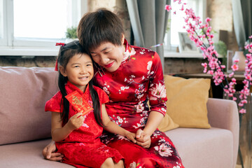 Happy Chinese woman embracing her little daughter with new year postcard