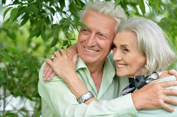 Portrait of happy senior woman and man hugging in park
