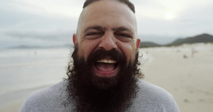 Happy latin man with big beard on a beach looking at camera and smiling. 4K.