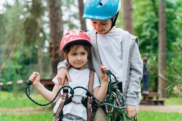 Obraz premium Positive, smiling little boy and girl in protective helmets. The brother hugs his little sister.