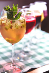Set of alcoholic cocktails in raw on a wooden table with green plaid tablecloth.