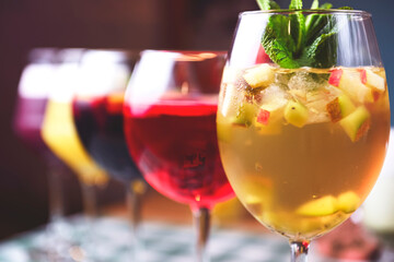 Set of alcoholic cocktails in raw on a wooden table with green plaid tablecloth.