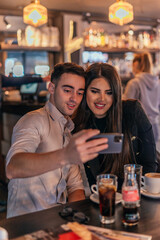 Front view of two business people making a selfie in the bar