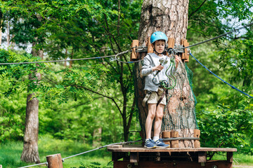 Little boy in a protective helmet prepares to walk on the cable car. A child in a rope park