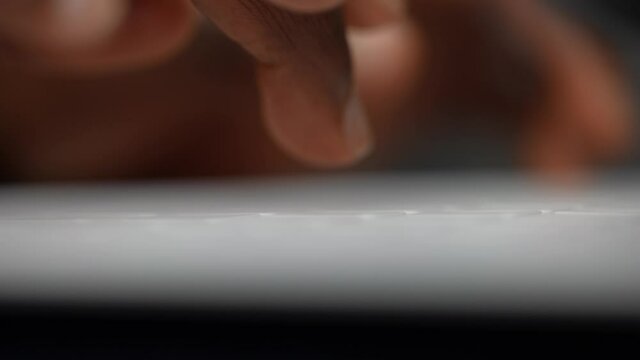 Super macro closeup shot of black African-American man's fingers typing on a white computer keyboard. Work, study. 