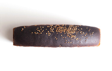 Loaf of black wheat bread with coriander seasoning on white plate, isolate. Healthy bread