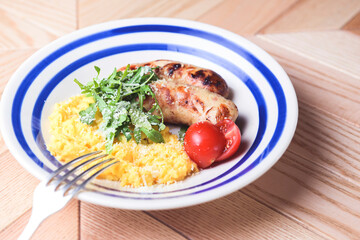 Risotto with pork sausages with cherry tomatoes and parsley on a plate. Italian cuisine concept