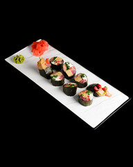 Maki Sushi set on a white plate over black background. Japanese cuisine concept, maki rolls.
