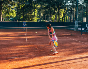 View from the back of a young female paying tennis on a court outside