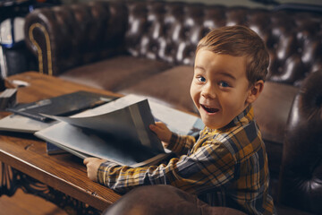 Little boy at the barbershop, in waiting room waiting for master.