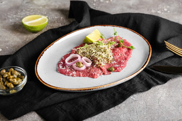 Plate with tasty veal carpaccio on grunge background