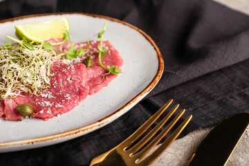 Plate with tasty veal carpaccio on table, closeup