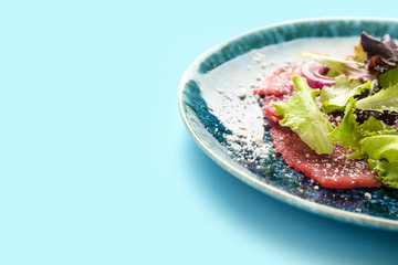 Plate with tasty veal carpaccio on color background, closeup