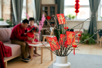Red Chinese new year postcards and lanterns hanging on dry branches in white vase