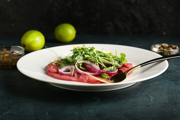 Plate with tasty veal carpaccio on dark background