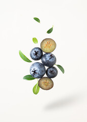 Concept flat lay with a  few juicy blueberries levitation with green leaves on yellow background. Front view and copy space