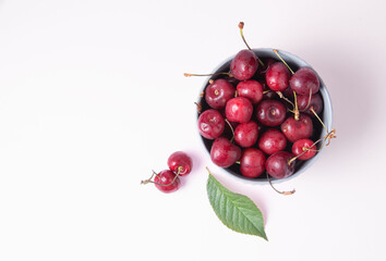 juicy red cherries in a gray bowl on a pink background. Top view and copy space