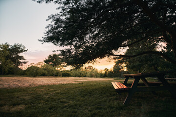 Public outdoor furniture in the park during amazing sunset sky while warm weather. City park with seats and tables for eating outdoors