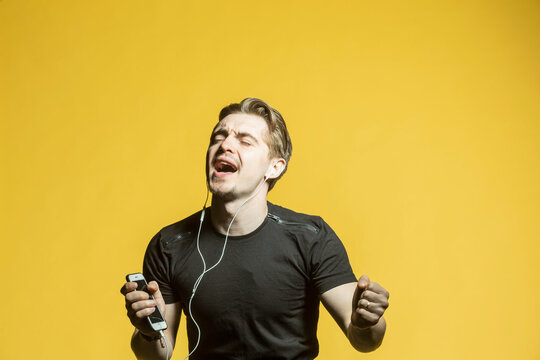 Carefree young man with mp3 player listening to music and singing
