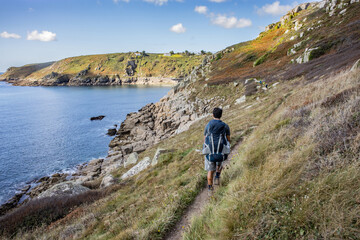 Hiker walks along the south west coast path near Lamorna cove beach, Penzer point in Cornwall