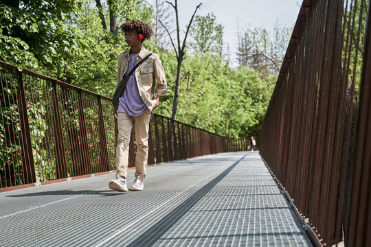 Man Wearing Headphones Walking Through The Bridge And Listening Music