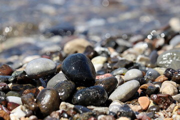 Wet pebble stones on blurred background of sea waves. Summer vacation concept
