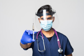 Study of COVID-19 infection. Male doctor examines medicine for illness, man in blue mask with syringe and jar