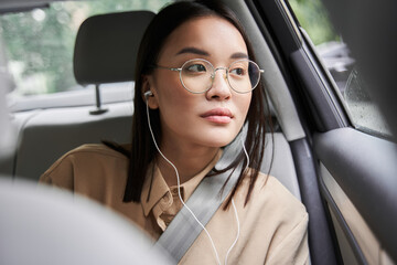 Businesswoman listening music and looking at the window while riding at the car