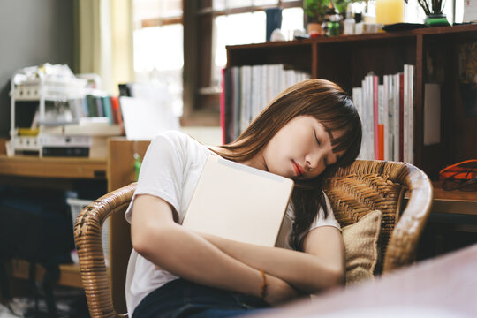 Asian teenager student woman hold digital tablet and take a sitting nap on chair stay at home.