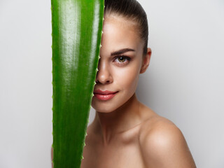 pretty woman with green aloe leaf before eyes clean skin cosmetology natural look health 