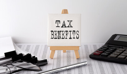 text TAX BENEFITS on easel with office tools and paper.Top view. Business concept