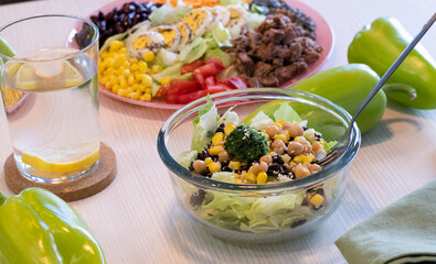 Salads with mix of fresh vegetables. Green paprika and glass of water with lemon on the table. Healthy  concept