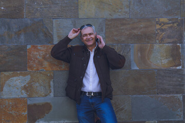 Obraz premium smiling man with sunglasses using mobile phone with wall background