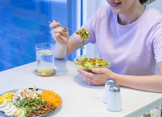 Pretty woman in purple shirt,  with hairband, eating salad on lunch break, living healthy lifestyle. Eating healthy fresh organic salad in restaurant. tasting salad while sitting on chair 