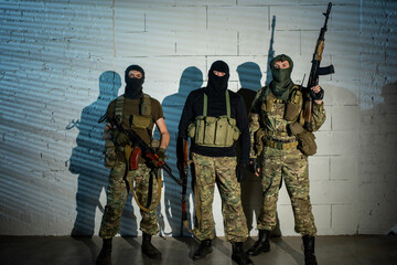 Group of unrecognizable officers in military outfit holding weapons - obrazy, fototapety, plakaty
