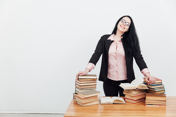 beautiful female teacher in business suit at a table with stacks of educational books