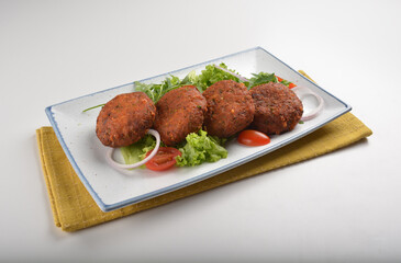 deep fried golden potato cake ball with greens salad in white background asian Indian appetiser halal menu